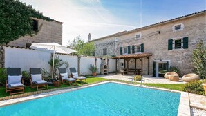 A swimming pool with lounge chairs and a pergola.