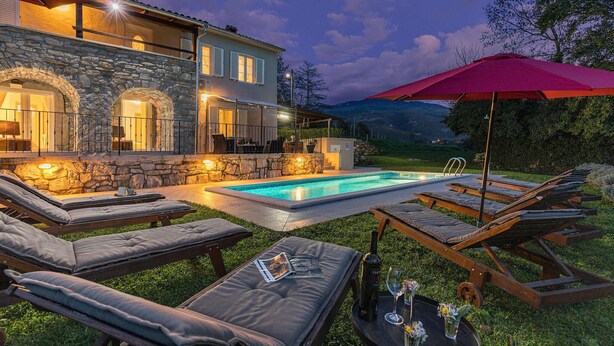 A poolside area with lounge chairs, a stone building, and a red umbrella. - Gorgeous home in Boljun (Boljun)
