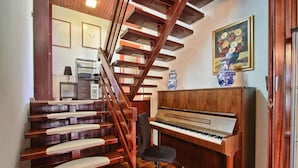 A staircase with wooden steps and a piano in a room with a tiled floor.