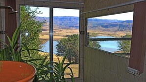 A room with a large sliding glass door leading to a scenic view of a river and mountains.