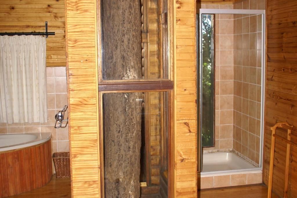 A wooden cabin bathroom with a bathtub, shower, and wooden walls.