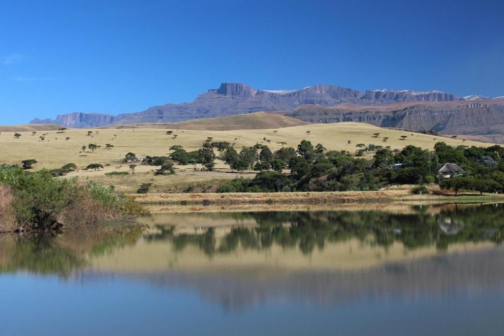 A serene landscape with a lake reflecting the surrounding hills and sparse vegetation.