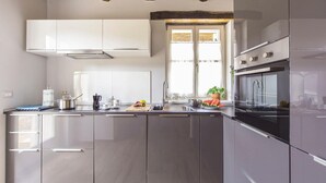 A modern kitchen with stainless steel appliances, a built-in oven, and a window with curtains.