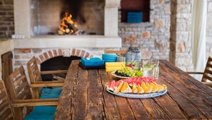 A wooden table with a plate of sliced watermelon and cantaloupe, a pitcher of iced tea, and a glass jar of grapes.