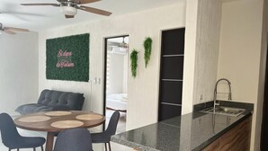 A modern kitchen with a central island, a dining area with a round table and chairs, and a ceiling fan. - ALDEA TULUM (Tulum)
