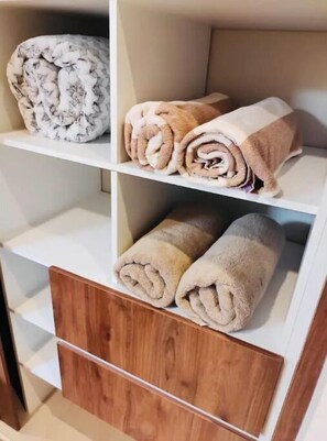 Storage area with shelving unit, featuring a top shelf for personal items and a middle shelf for towels.