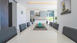 A modern dining area with a white table, grey chairs, and a decorative centerpiece. - Stunning home in Kostrena with sauna (Kostrena)