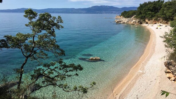 A beach with clear turquoise water, a sandy shore, and a backdrop of mountains. - Stunning home in Kostrena with sauna (Kostrena)
