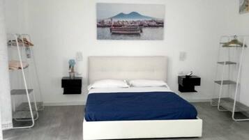 A bedroom with a bed, a nightstand, a wall-mounted shelf, and a picture of a boat on water.