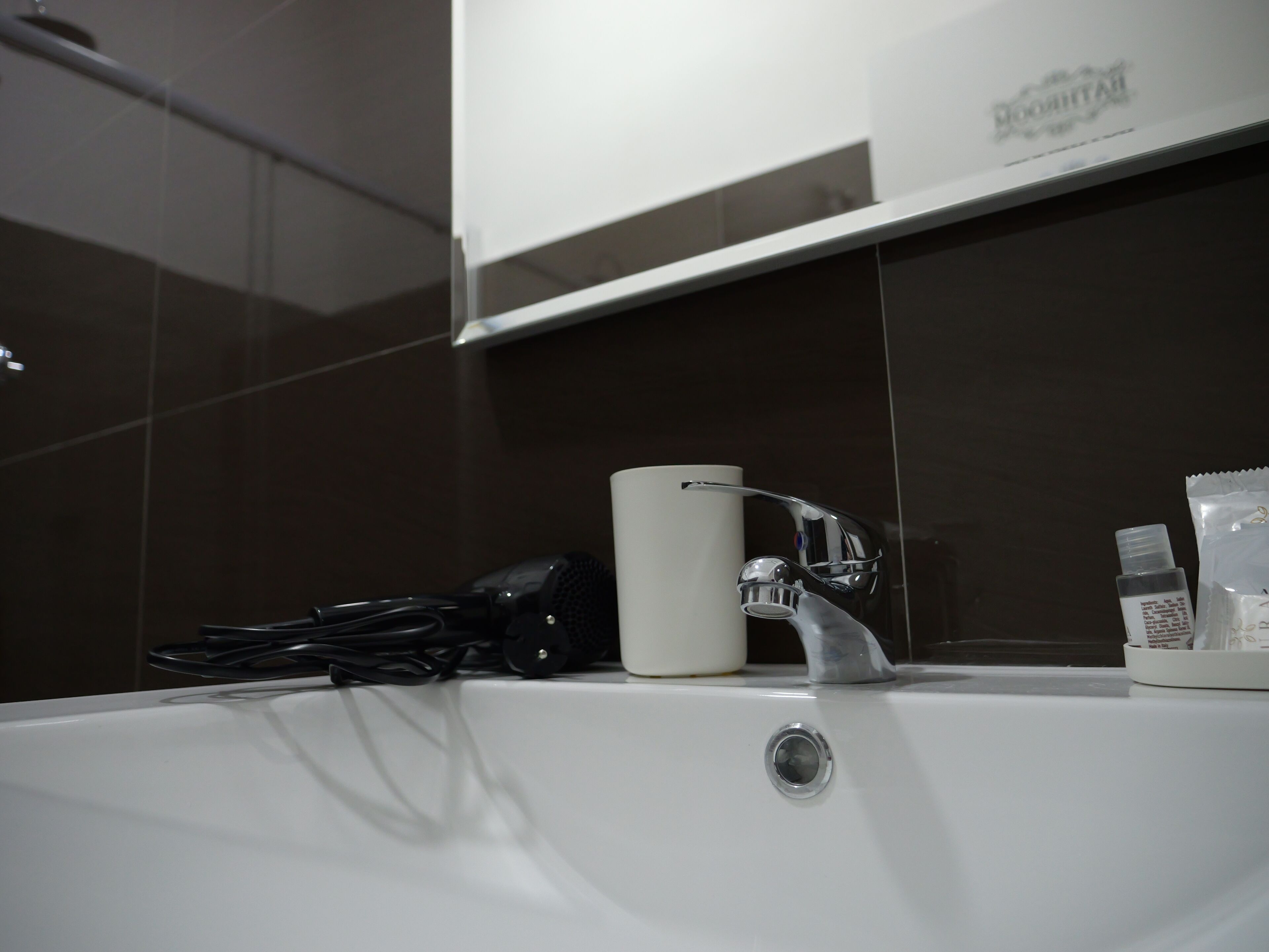 A bathroom with a white sink, a mirror, and a towel rack.