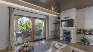Un salon moderne comprenant un canapé, un téléviseur, une cheminée et un coin repas avec des chaises et une table.