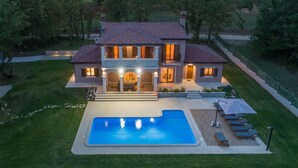 Une maison à deux étages dotée d’une piscine, d’un patio couvert et d’une pelouse bien entretenue.