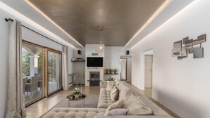 Un salon moderne doté d’un grand canapé d’angle, d’un téléviseur à écran plat et d’un coin repas avec des meubles en rotin.