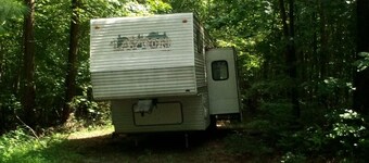Camper off home in wooded property small creek.