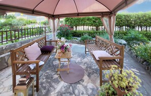 Relax in a serene outdoor seating area surrounded by lush greenery and a beautiful stone wall.