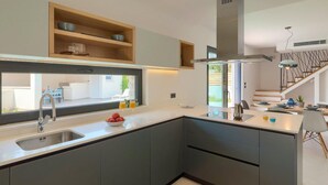 A modern kitchen with a large window, built-in shelves, and a central island.