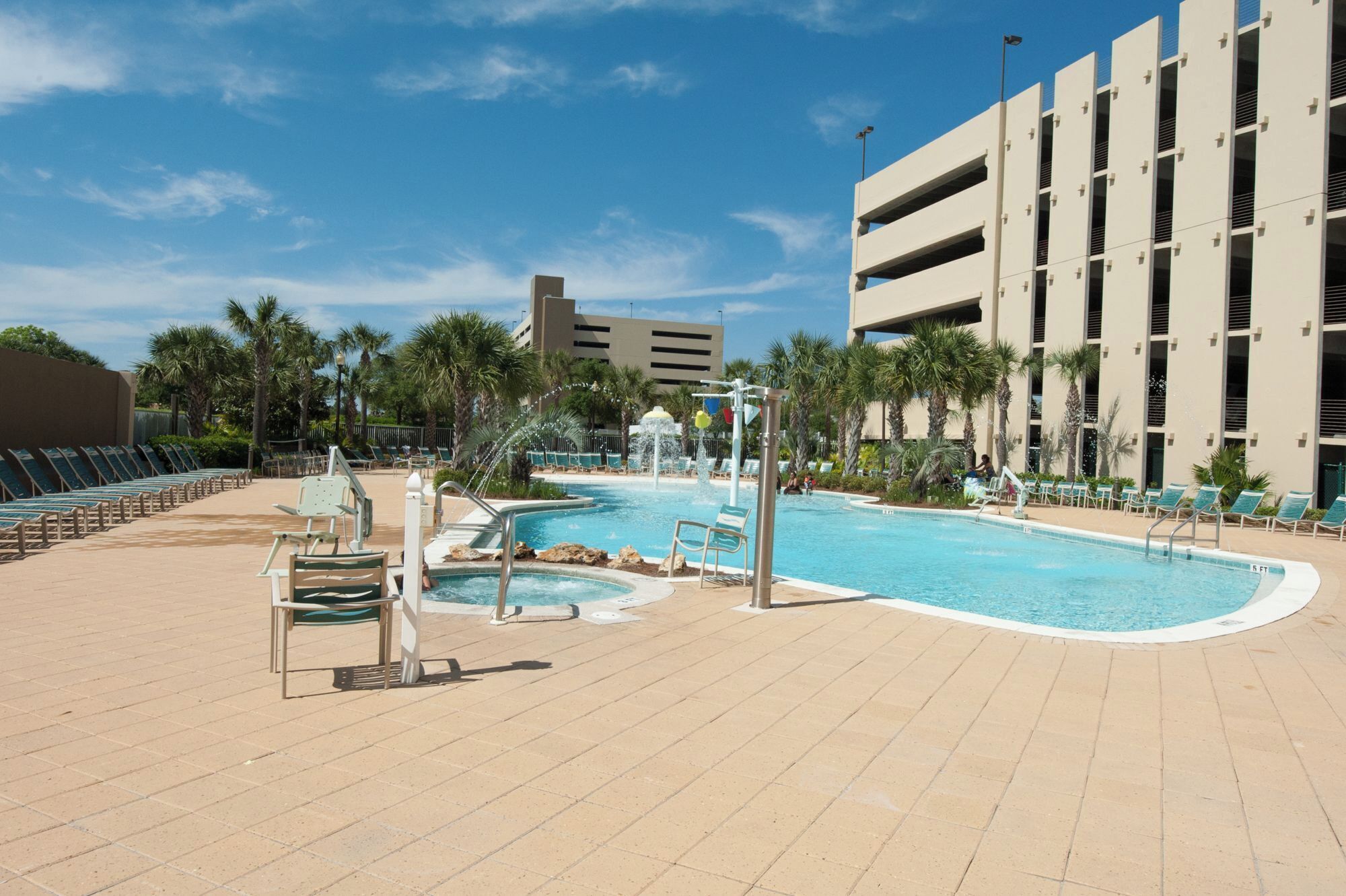 A swimming pool area with lounge chairs and a water fountain.