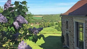 A stone building with a red roof, large windows, and a view of a green landscape. - Maison DE Charme, 2 Pigeonniers ET Piscine (Saint-Rémy)