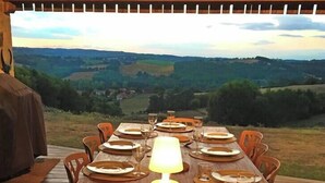 A wooden dining table set for six with plates, cutlery, and a candle, overlooking a scenic landscape. - Maison DE Charme, 2 Pigeonniers ET Piscine (Saint-Rémy)