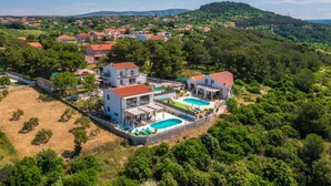 A residential area with houses, a swimming pool, and a hilly landscape in the background. - Stunning home in Sibenik (Sibenik)