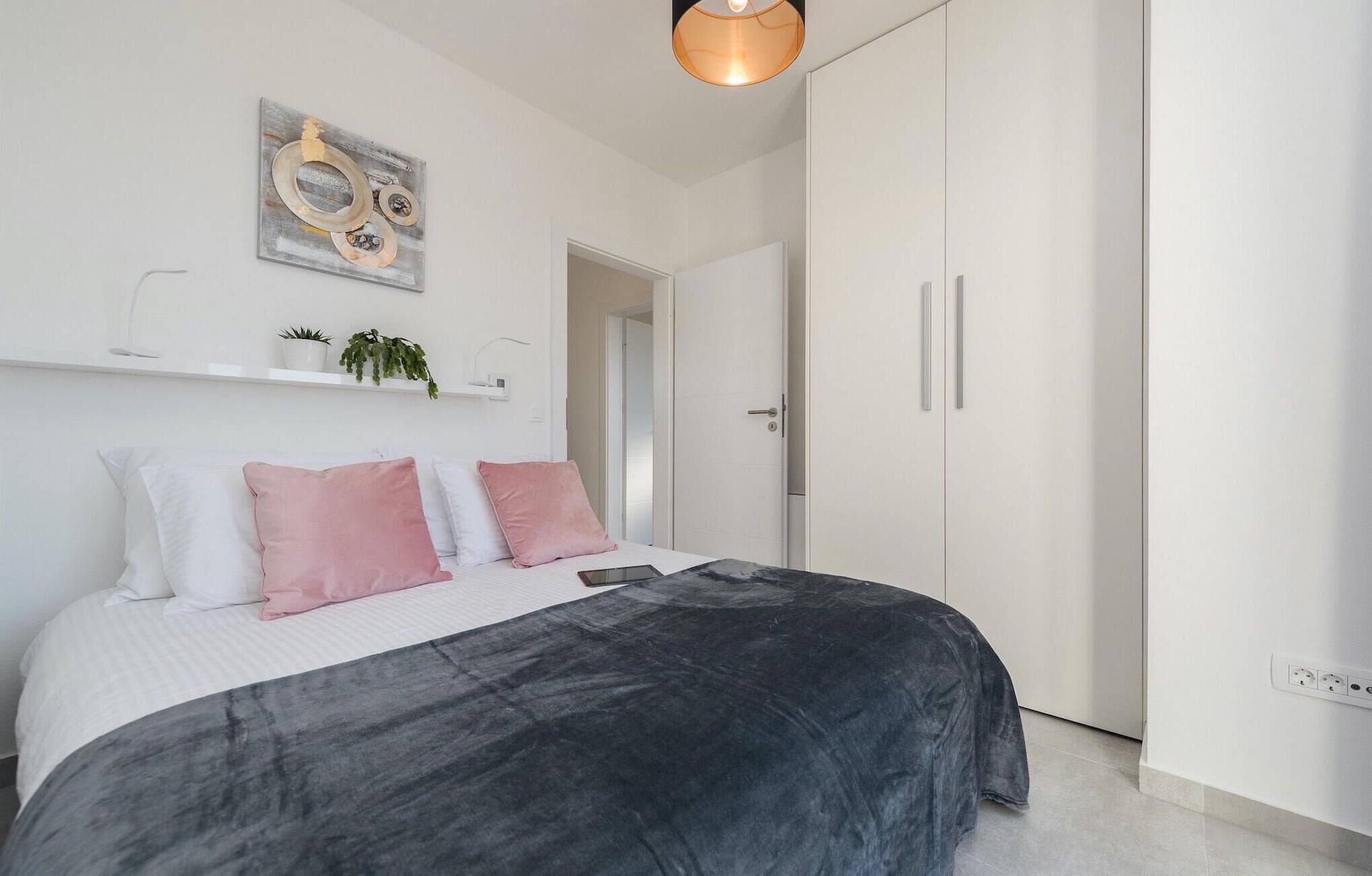 Una camera da letto moderna con un letto, uno scaffale a parete con piante e una porta che dà su un'altra stanza.