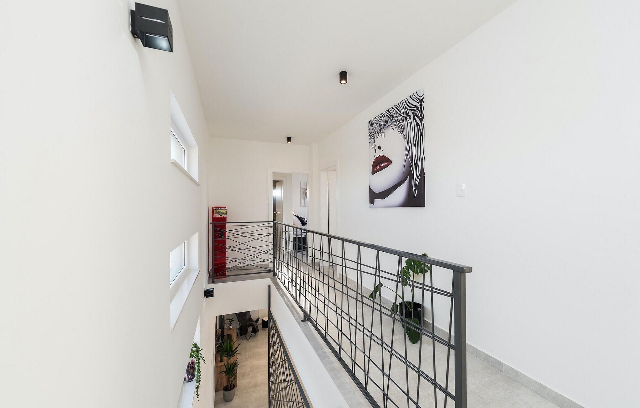 A modern interior with a staircase, metal railings, and a large abstract painting on the wall.