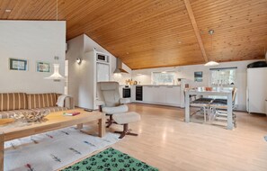 Une cuisine moderne avec des meubles blancs, un coin repas avec une table et des chaises, et un salon avec un canapé et une table basse.