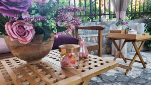 A wooden table with a vase of flowers, a glass jar of candies, and a pink bottle. - 1 bedroom lovely apartment in Zadar (Zadar)