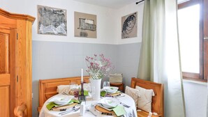A dining area with a wooden table set for two, a vase with flowers, and artwork on the wall. - 1 bedroom lovely apartment in Zadar (Zadar)