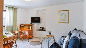 A living room with a TV, a map, a sewing machine, a wooden desk, a chair, and a sofa. - 1 bedroom lovely apartment in Zadar (Zadar)