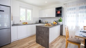 A modern kitchen with white cabinets, a central island, and a dining area with a table and chairs. - Gorgeous home in Kanfanar (Kanfanar)