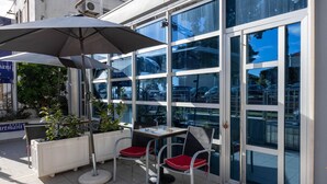 An outdoor seating area with a table and two chairs, a potted plant, and a large umbrella. - Stunning apartment in Kastel Novi with WiFi (Kastel Novi)