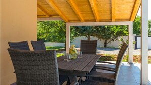 Une terrasse extérieure avec une table en bois et des chaises en osier.