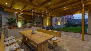 Une terrasse extérieure avec une table et des bancs en bois, entourée de plantes en pot et d’un mur de pierre.