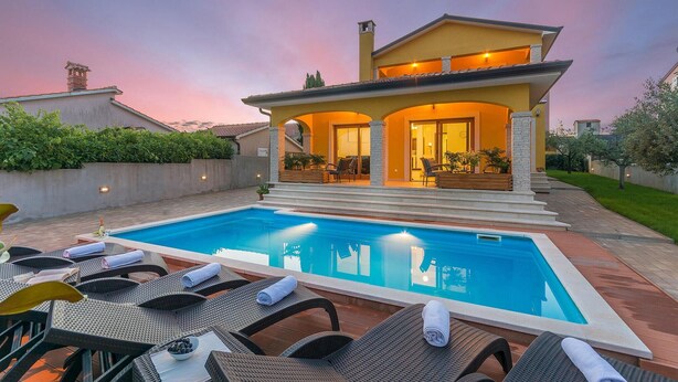 Une maison moderne à deux étages, dotée d’une piscine, d’un espace extérieur aménagé et d’un jardin bien entretenu.