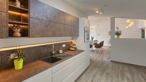 Una cuina moderna amb un fanal, prestatges integrats, un rentaplat i una zona menjador amb cadires.