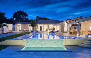 A modern house with a swimming pool, outdoor seating, and a well-lit patio area. - Stunning home in Pula (Pula)