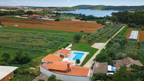 Una casa gran amb piscina, envoltada de camps i un llac.