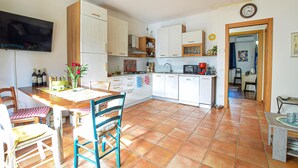 Une cuisine de taille réduite avec des meubles blancs, un coin repas comprenant une table et des chaises en bois, et un sol carrelé.