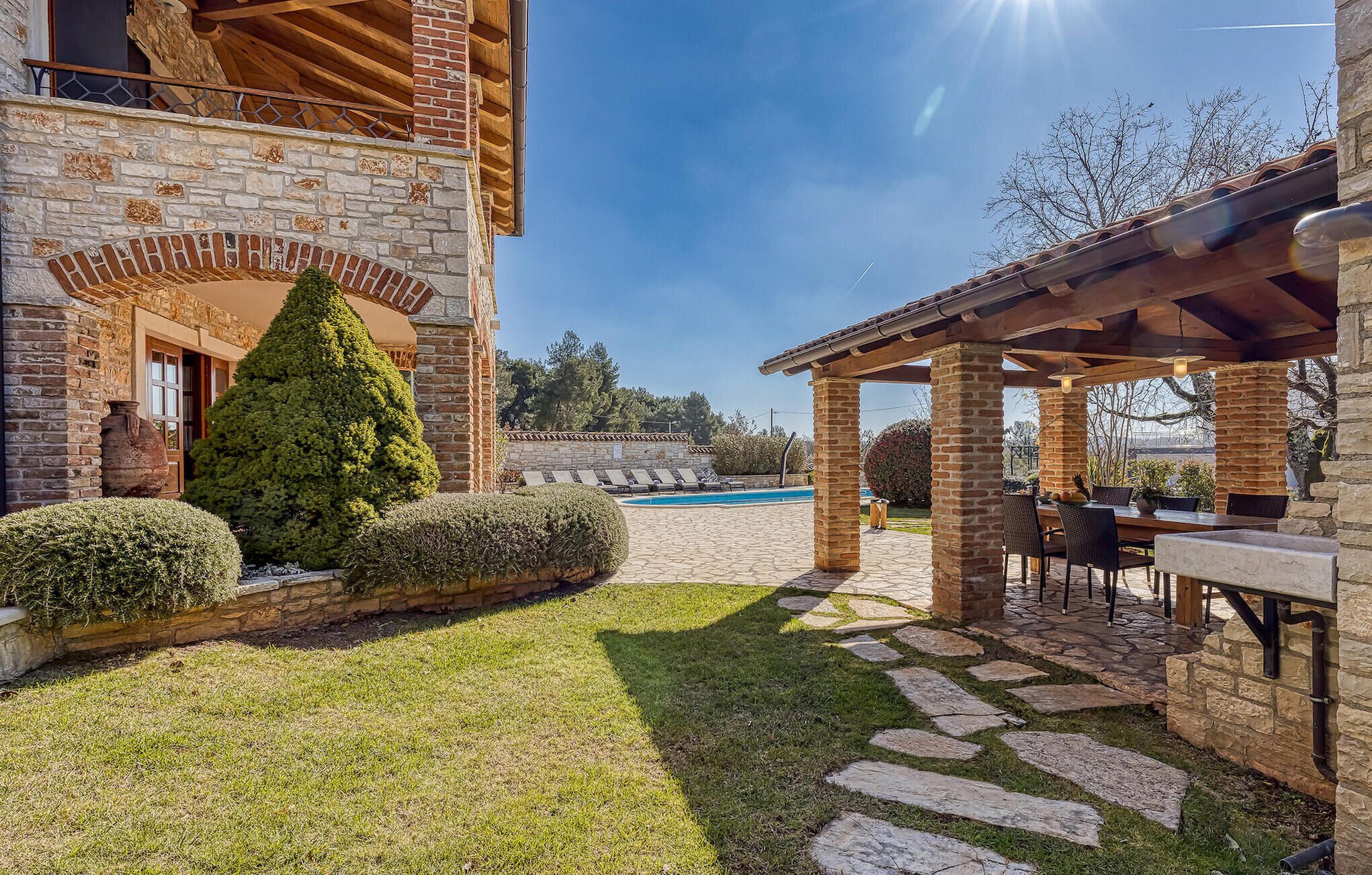 Un bâtiment en pierre doté d’une piscine, d’un patio couvert et d’une pelouse bien entretenue.