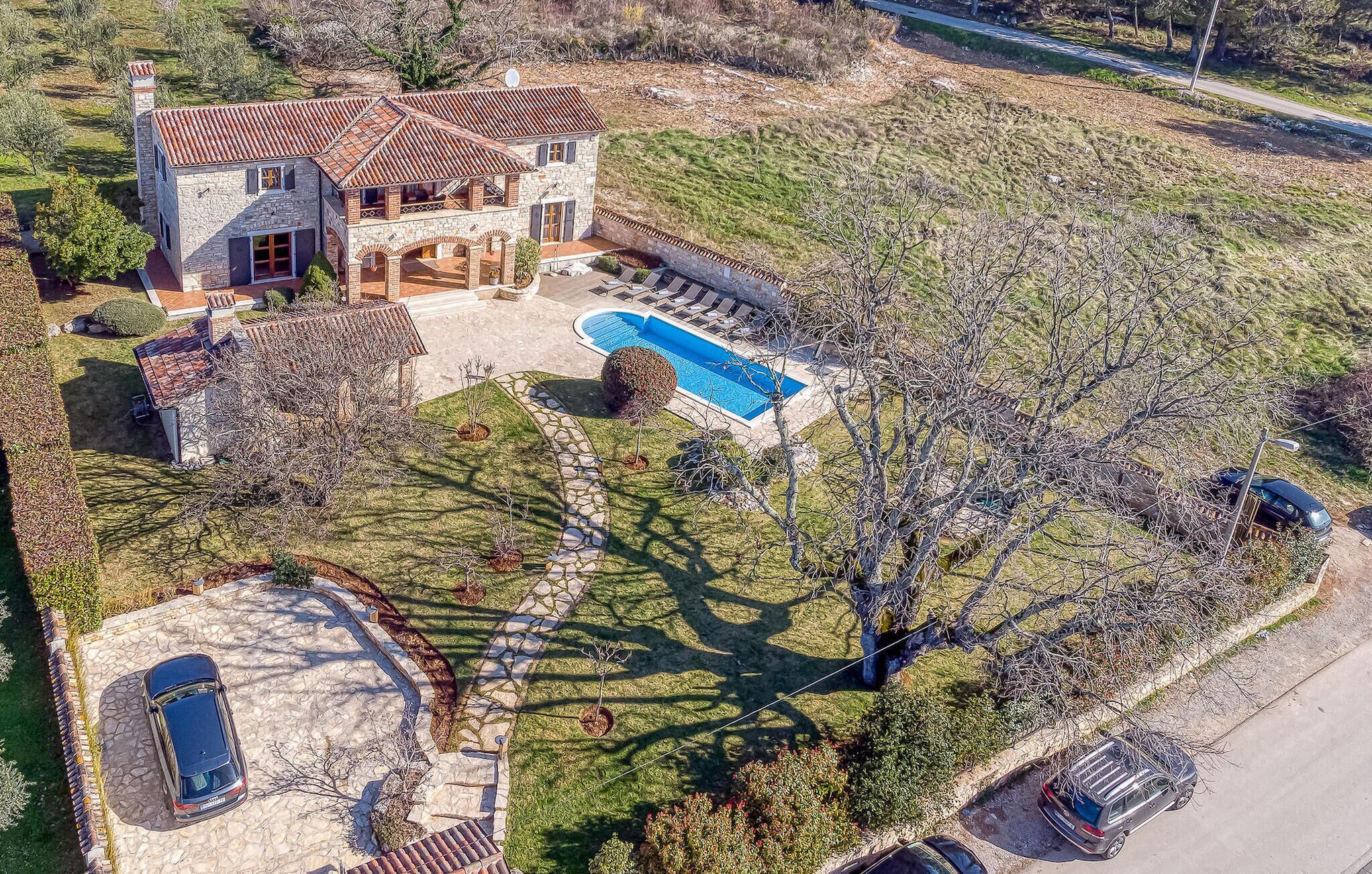 A large house with a swimming pool, stone exterior, and a well-maintained lawn.