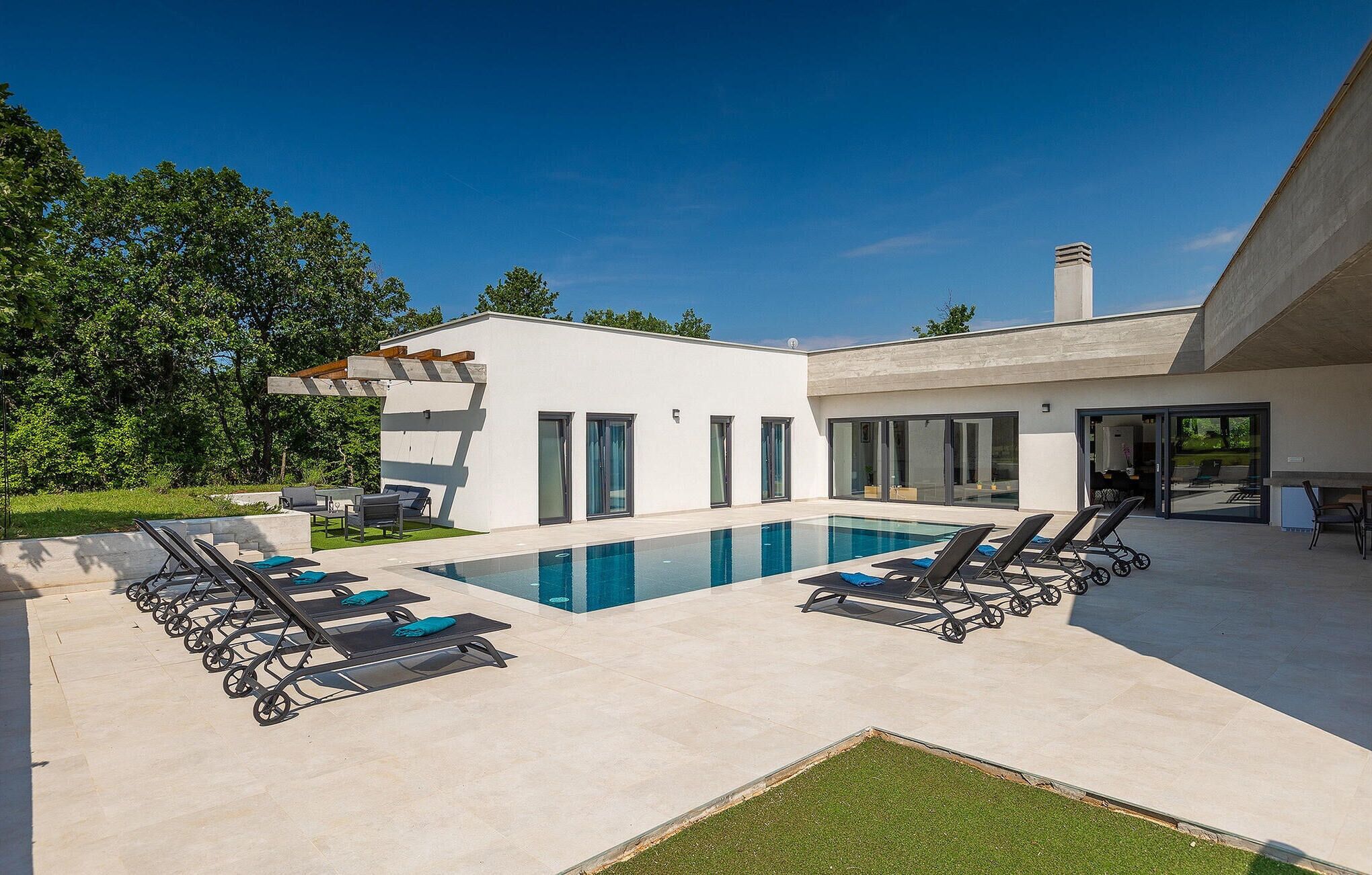 Een modern huis met een zwembad, terras en een verzorgd gazon.