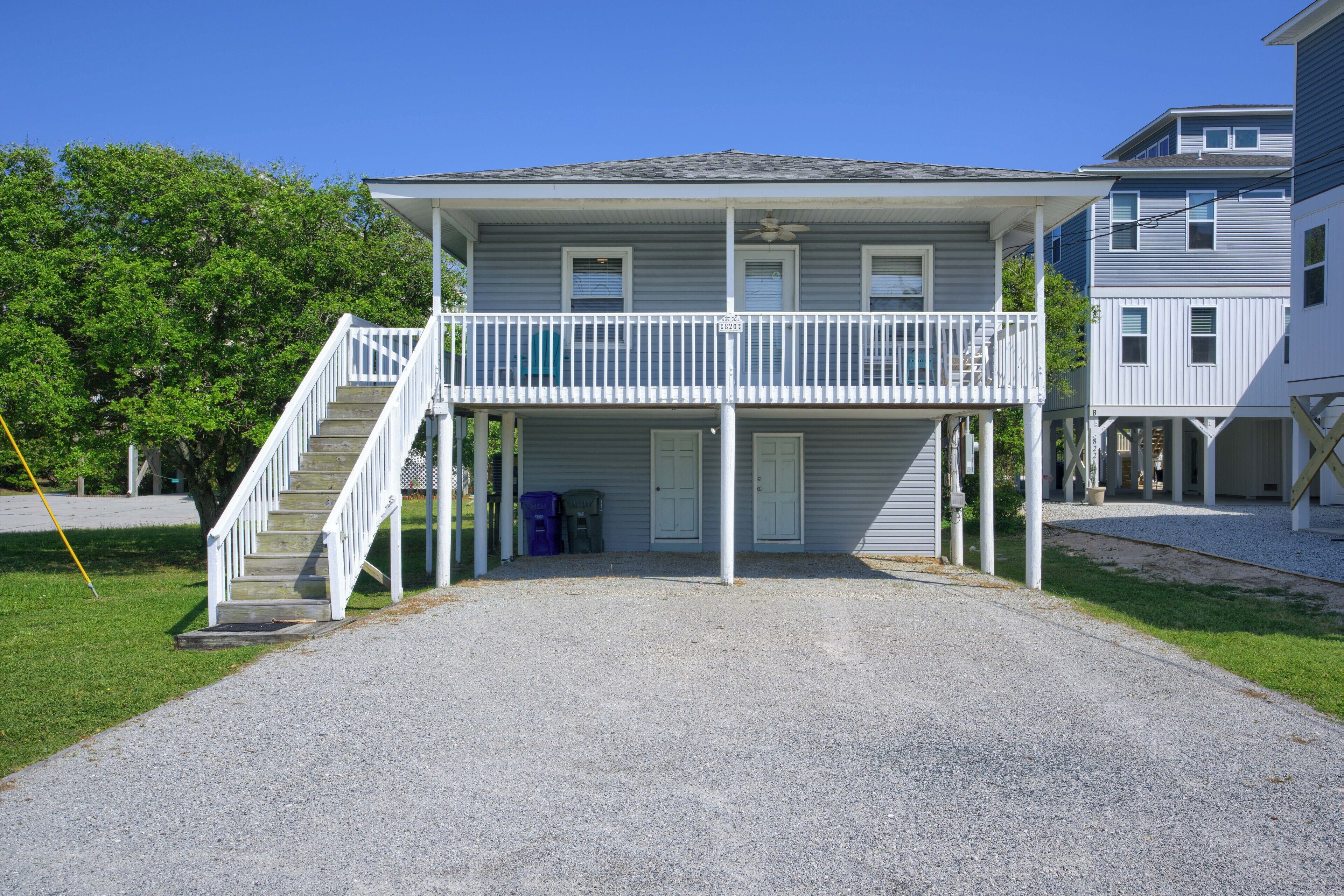 A two-story building with a covered front porch and a staircase leading to a balcony.