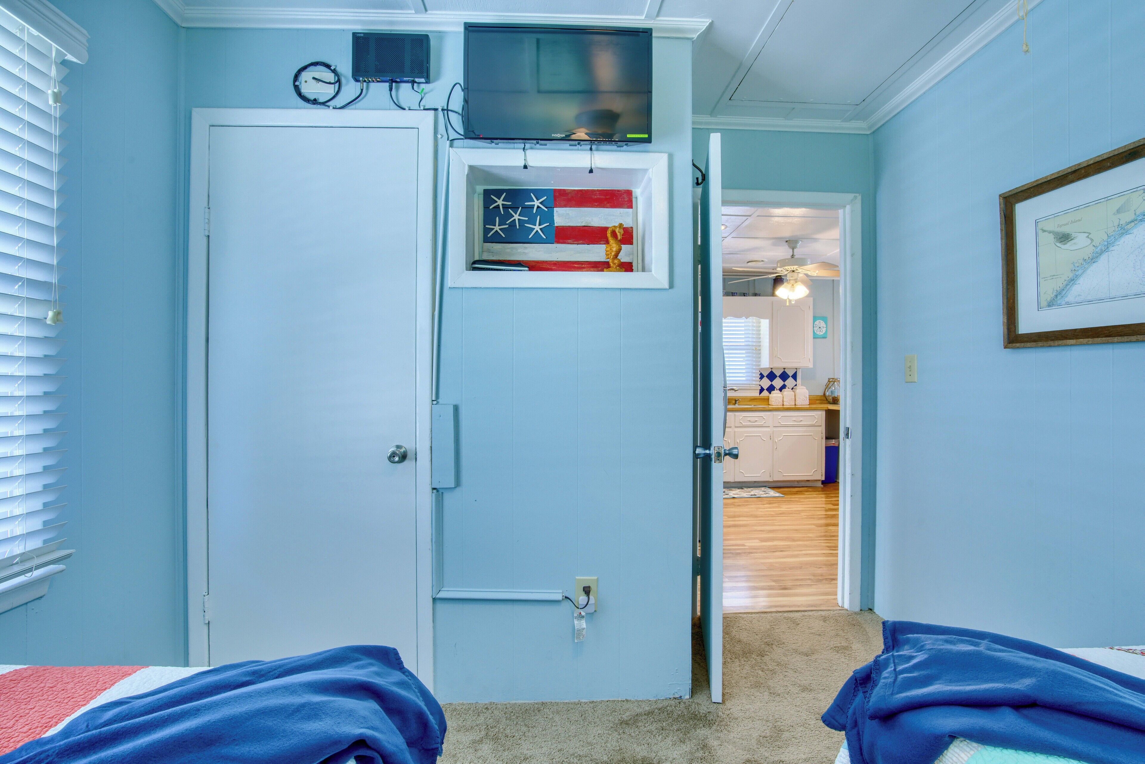 A room with a closed door, a television mounted above it, and a small American flag decoration.