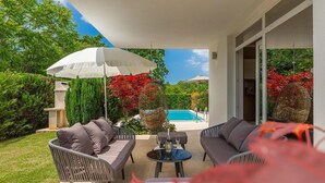 Une terrasse extérieure avec des meubles en osier, une piscine et un feuillage rouge.