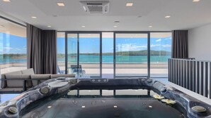A modern spa room with a hot tub, large windows offering a view of the sea, and a balcony with seating. - Beautiful home in Medulin with sauna (Medulin)