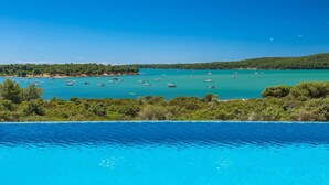 A coastal view with a swimming pool in the foreground and boats on the water. - Beautiful home in Medulin with sauna (Medulin)