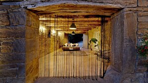 Une pièce avec un mur en pierre, un plafond en bois et un luminaire suspendu.