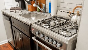 Una cocina con estufa de acero inoxidable, un lavabo y armarios de madera.