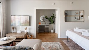 A modern hotel room with a large bed, a desk with a computer, a television, and a bathroom visible through an open door. - Stylish and Comfy Studio near Loyola Park (Chicago)